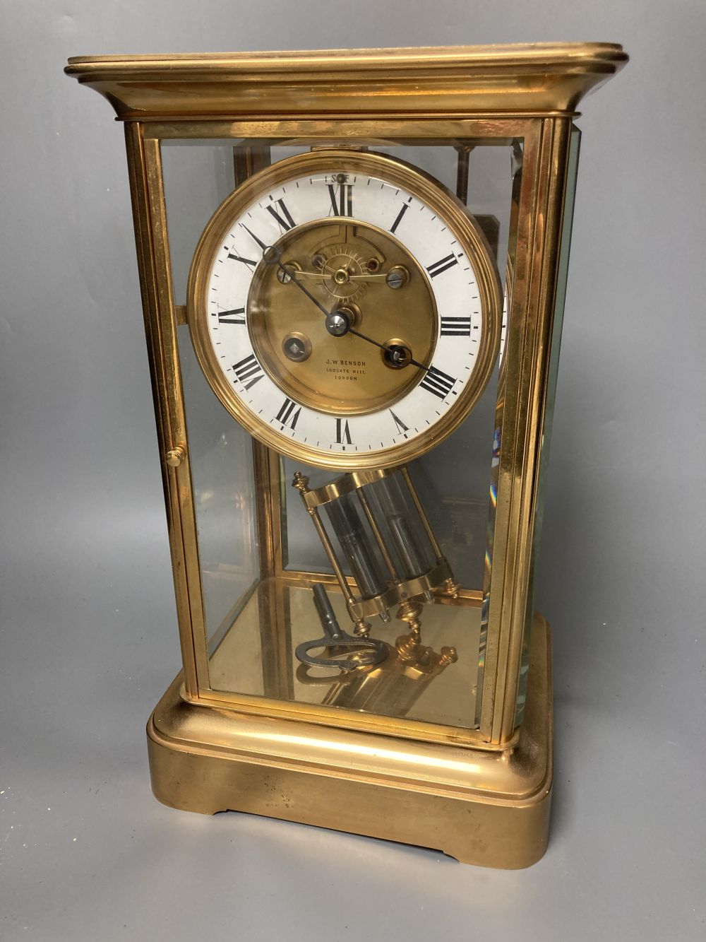 A French brass four glass mantel clock, retailed by J W Benson, with visible Brocot escapement and mercury filled pendulum bob, 33cm hi